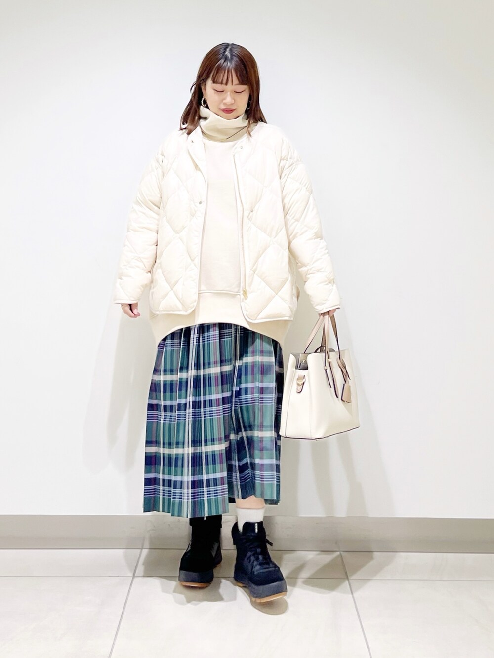 ベージュ系のスウェット、ホワイト系のダウンジャケット/コート、グリーン系のスカートを着用したレディースの秋コーディネートの5枚目の写真