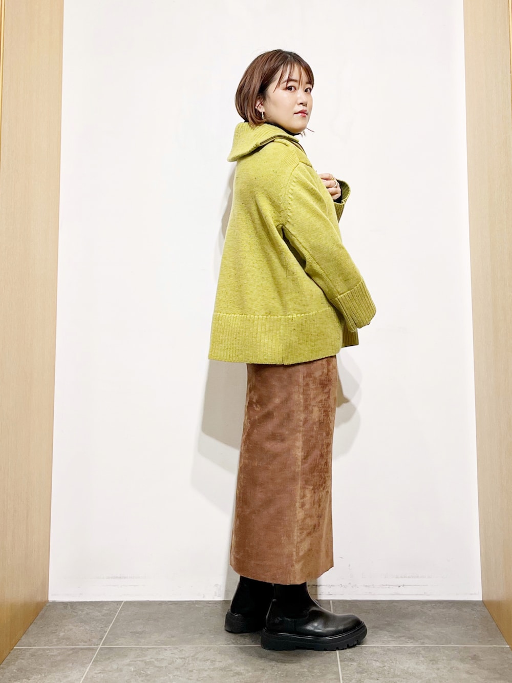 グリーン系のニット/セーター、ブラック系のニット/セーター、ブラウン系のスカートを着用したレディースの冬コーディネートの4枚目の写真