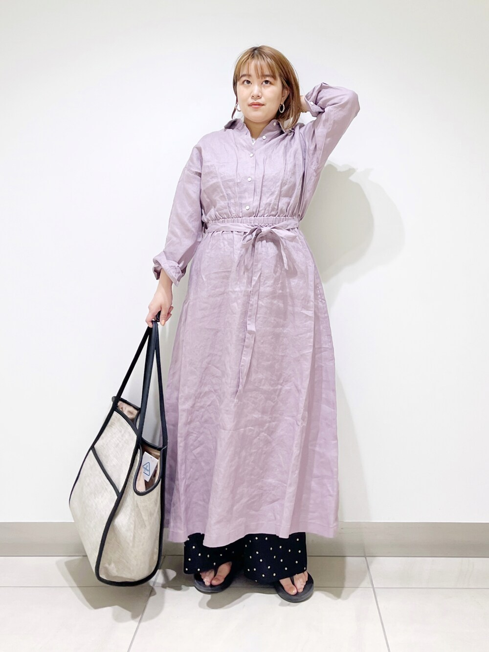 パープル系のワンピース、ブラック系のトートバッグ、ブラック系のサンダルを着用したレディースの春コーディネートの3枚目の写真