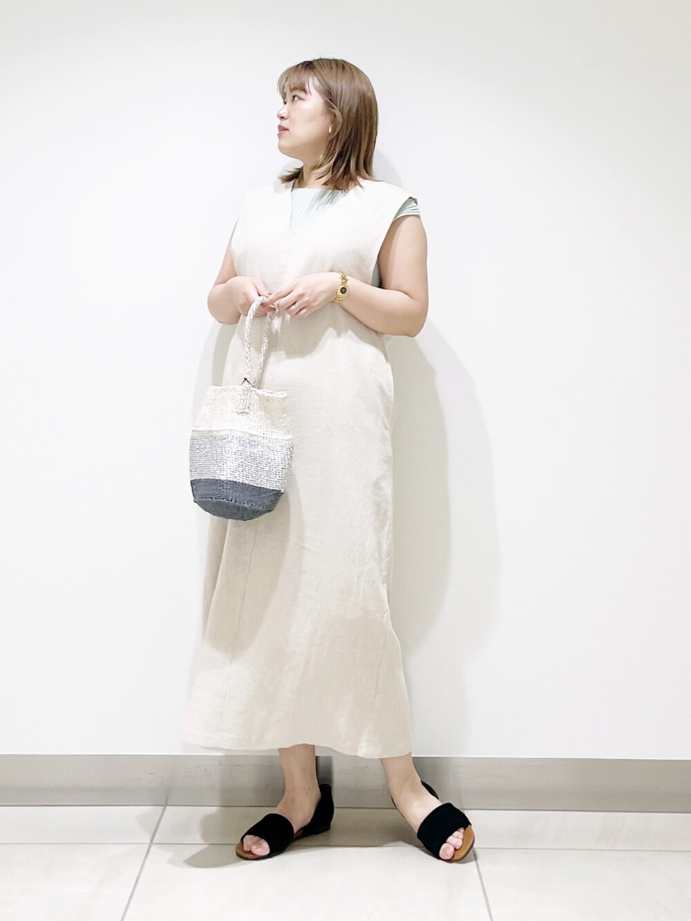 ベージュ系のワンピース、その他のハンドバッグ、ブラック系のサンダルを着用したレディースの夏コーディネートの3枚目の写真