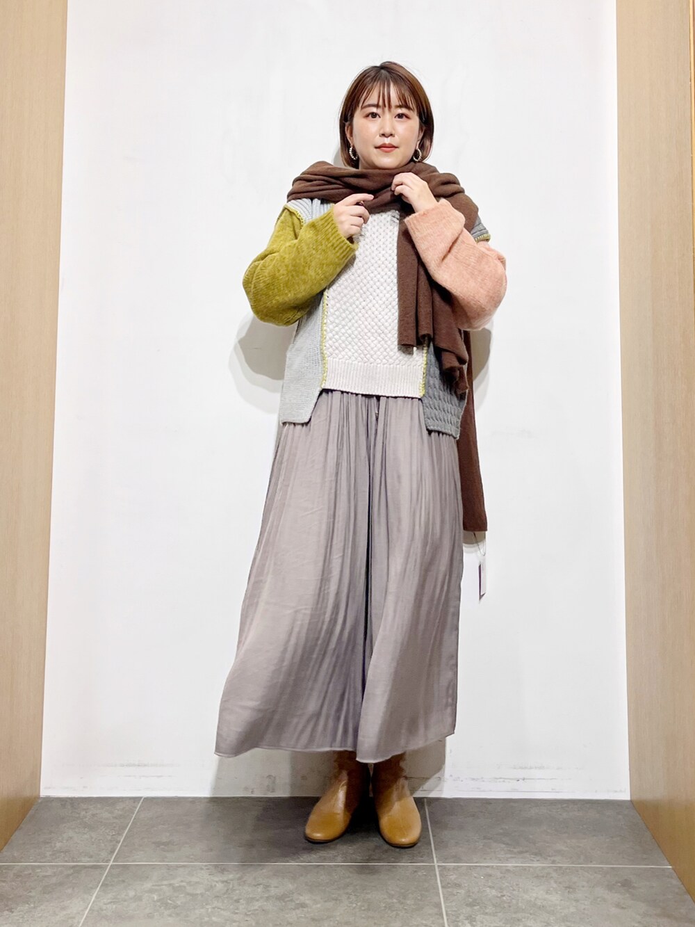 イエロー系のニット/セーター、グレー系のその他パンツ、イエロー系のブーツを着用したレディースの秋コーディネートの2枚目の写真