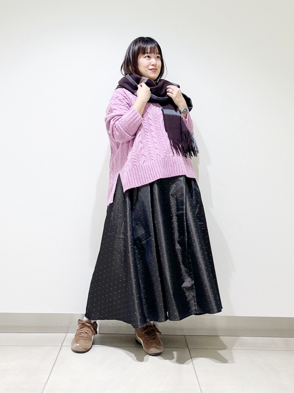 パープル系のニット/セーター、ブルー系のスカート、ブラック系のスニーカーを着用したレディースの秋コーディネートの4枚目の写真