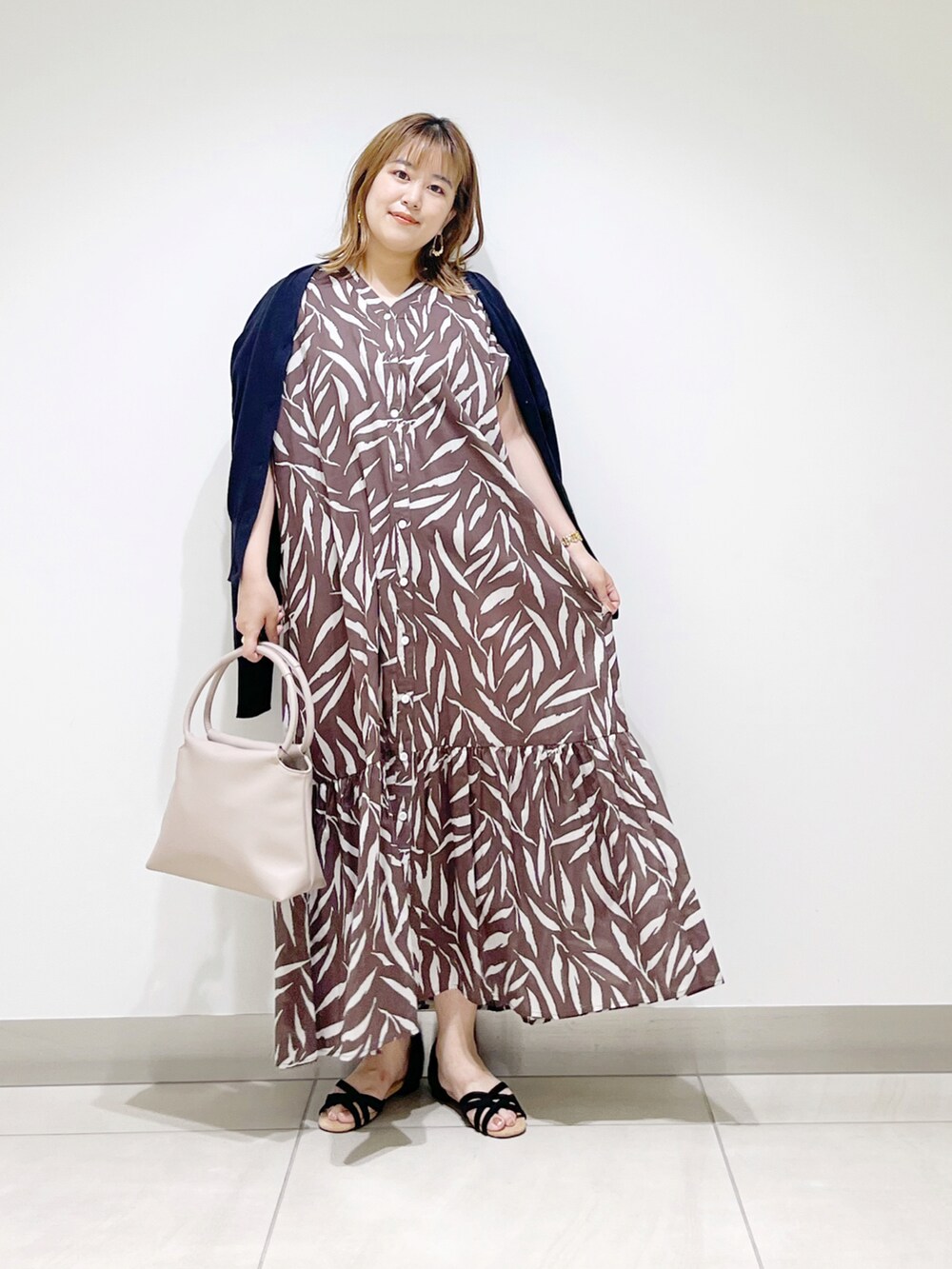 ブラウン系のワンピース、ベージュ系のハンドバッグ、ブラック系のサンダルを着用したレディースの夏コーディネートの3枚目の写真