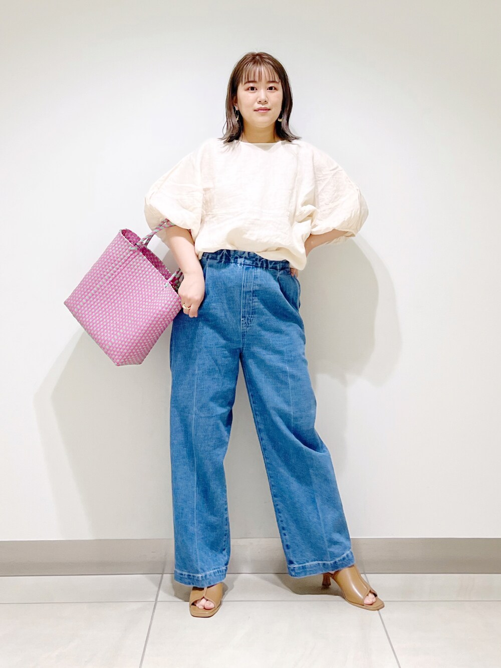ベージュ系のシャツ/ブラウス、ピンク系のトートバッグ、ブルー系のデニムパンツを着用したレディースの春コーディネートの3枚目の写真