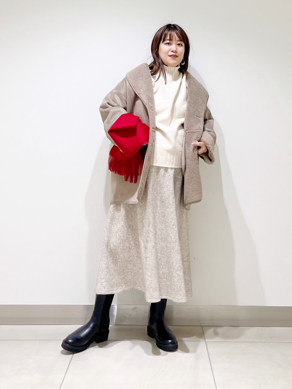グレー系のムートンコート、ホワイト系のニット/セーター、ベージュ系のスカートを着用したレディースの冬コーディネートの2枚目の写真