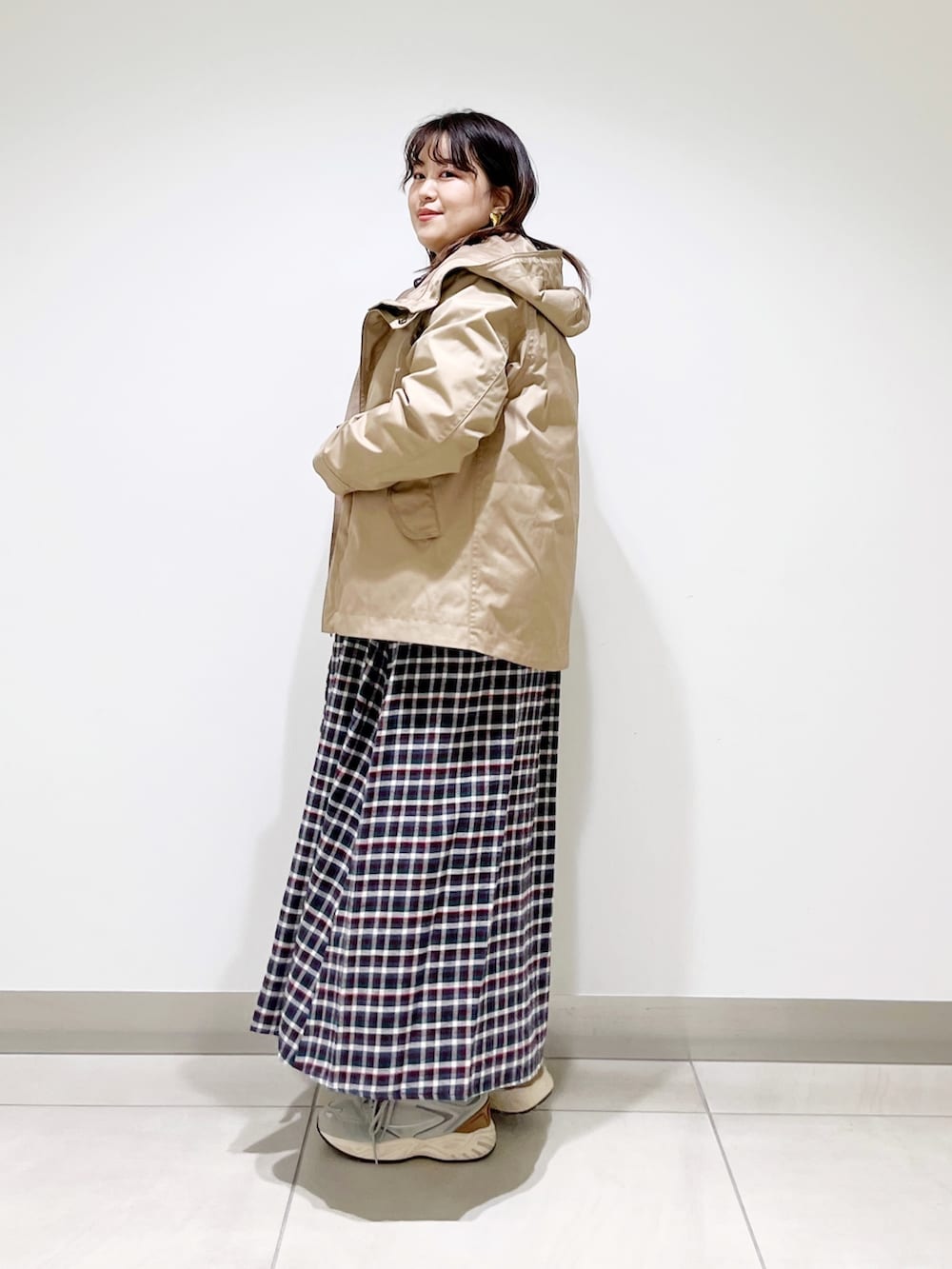 ベージュ系のマウンテンパーカー、ブラウン系のワンピース、グレー系のスニーカーを着用したレディースの春コーディネートの3枚目の写真