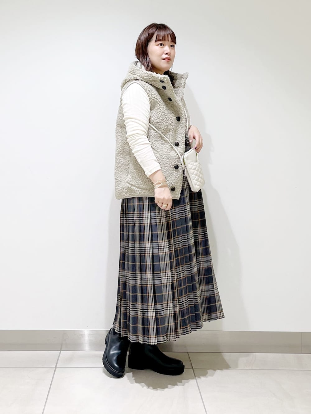 ホワイト系のトップス、グレー系のスカート、ブラック系のブーツを着用したレディースの秋コーディネートの3枚目の写真