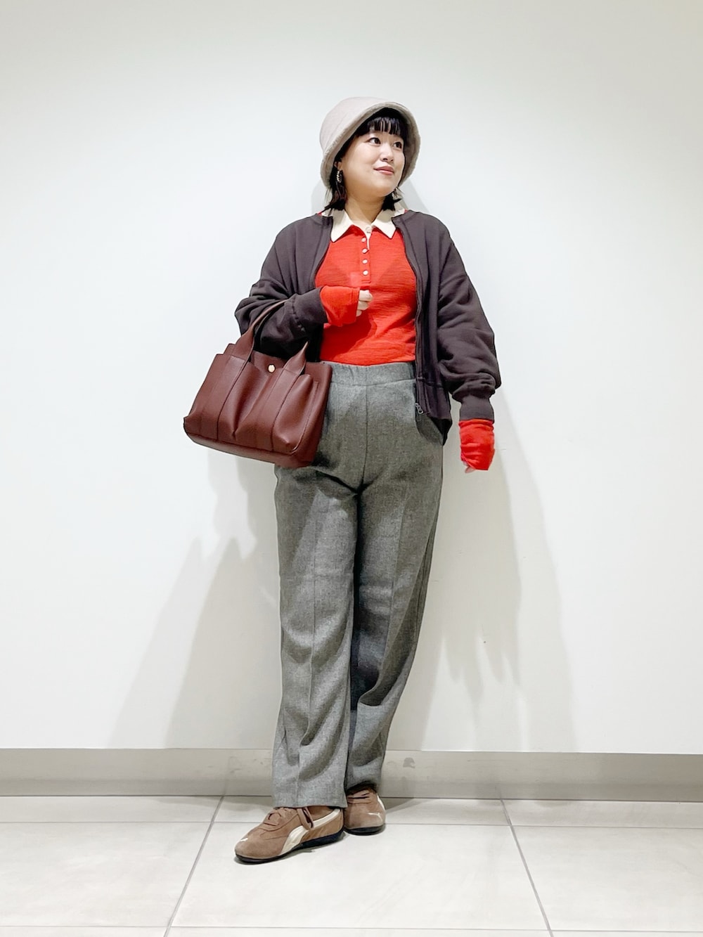 レッド系のニット/セーター、グレー系のその他パンツ、ブラック系のスニーカーを着用したレディースの秋コーディネートの2枚目の写真