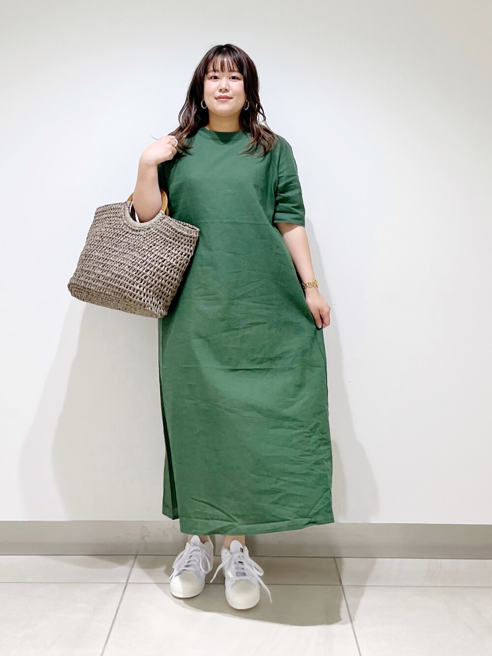 グリーン系のワンピース、グレー系のかごバッグ、ホワイト系のスニーカーを着用したレディースの夏コーディネートの9枚目の写真