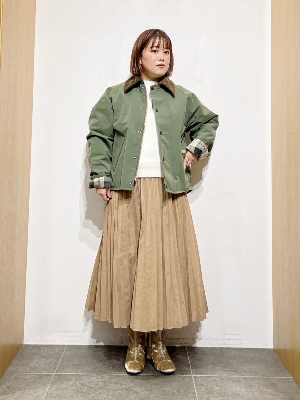 グリーン系のその他アウター、ホワイト系のニット/セーター、イエロー系のスカートを着用したレディースの秋コーディネートの2枚目の写真