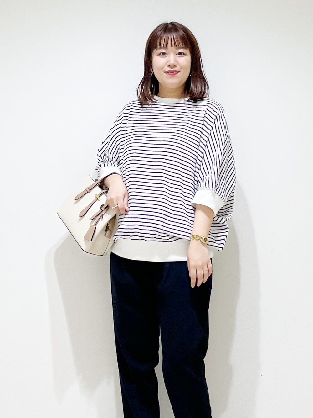 ホワイト系のTシャツ/カットソー、ブルー系のパンツ、ホワイト系のハンドバッグを着用したレディースの秋コーディネートの4枚目の写真