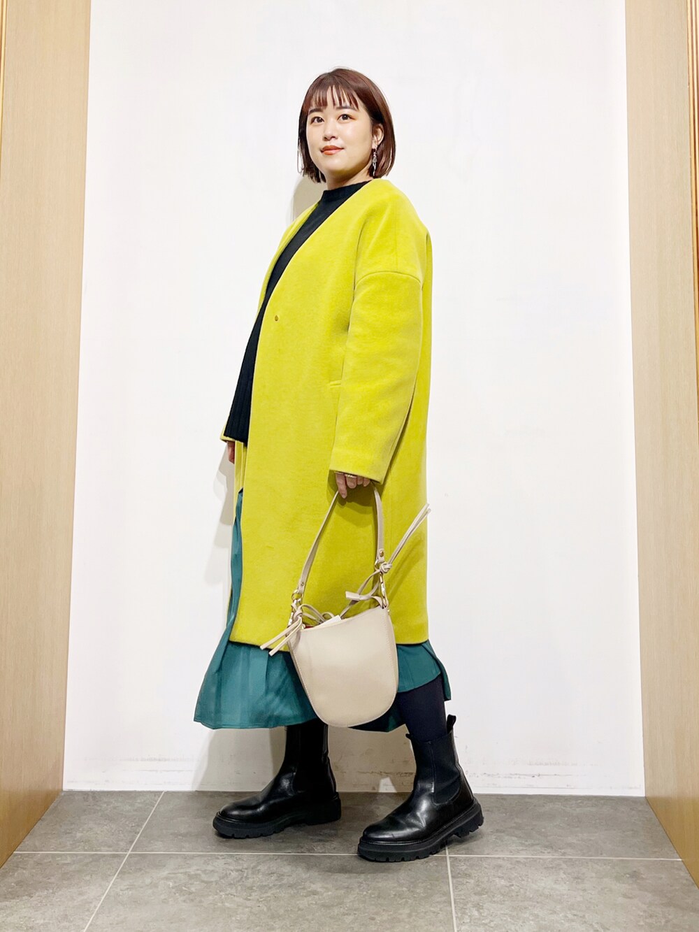 ブラック系のニット/セーター、イエロー系のその他アウター、グリーン系のスカートを着用したレディースの冬コーディネートの5枚目の写真