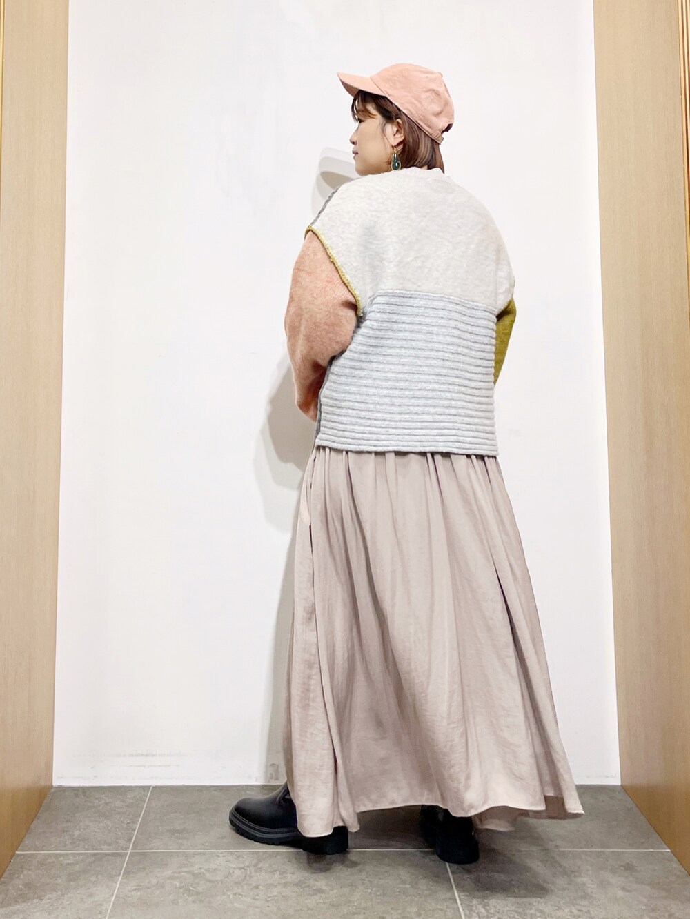 イエロー系のニット/セーター、グレー系のワンピース、ブラック系のブーツを着用したレディースの秋コーディネートの5枚目の写真