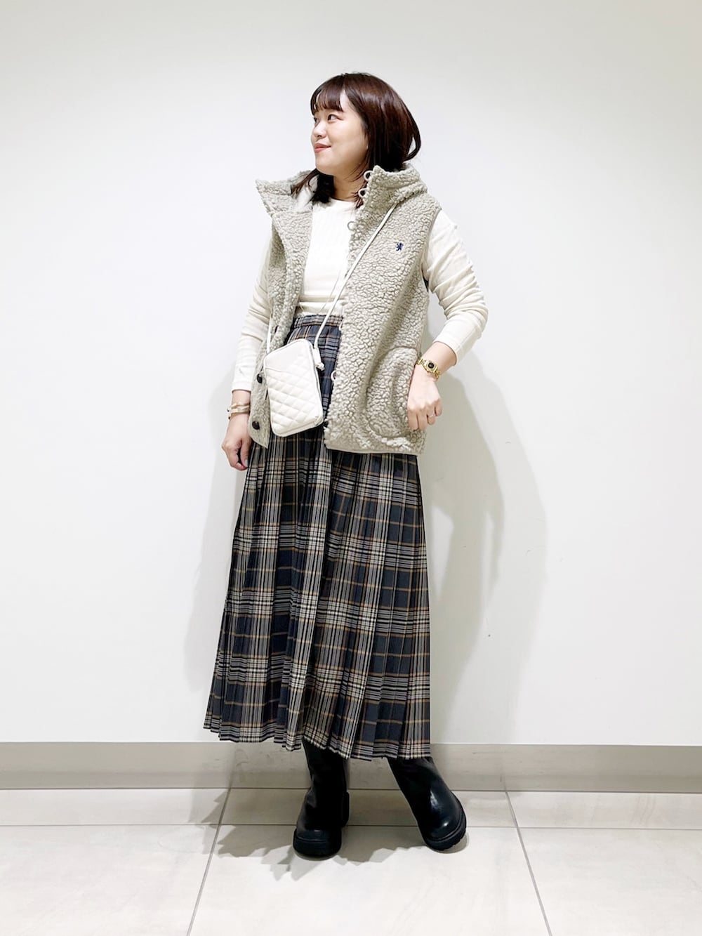 ホワイト系のトップス、グレー系のスカート、ブラック系のブーツを着用したレディースの秋コーディネートの2枚目の写真