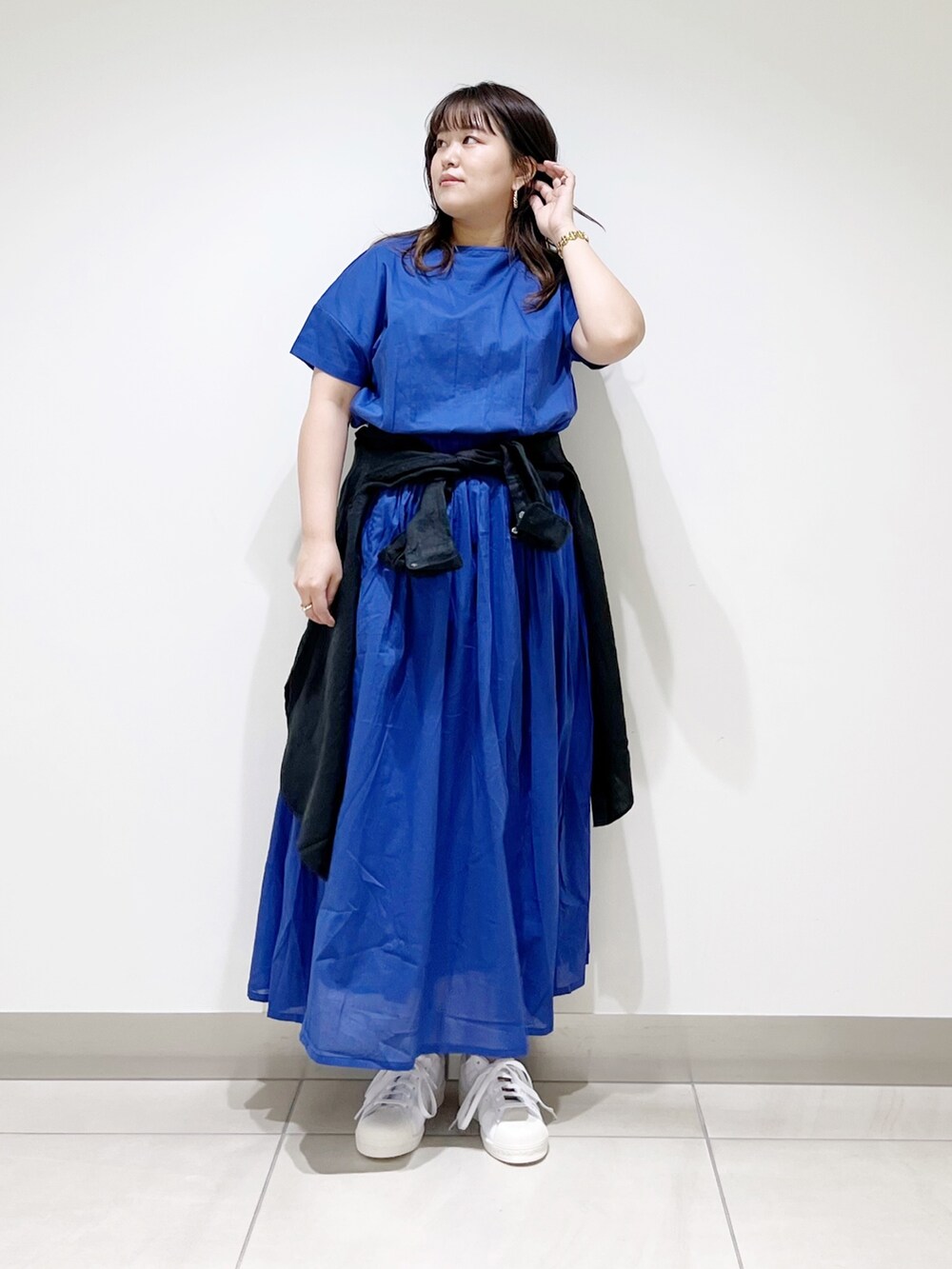 ブルー系のワンピース、ブラック系のシャツ/ブラウス、ホワイト系のスニーカーを着用したレディースの春コーディネートの2枚目の写真