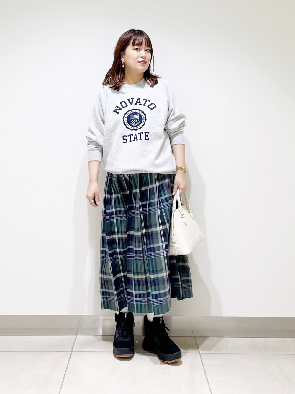 グリーン系のスカート、グレー系のスウェット、ホワイト系のショルダーバッグを着用したレディースの冬コーディネートの8枚目の写真