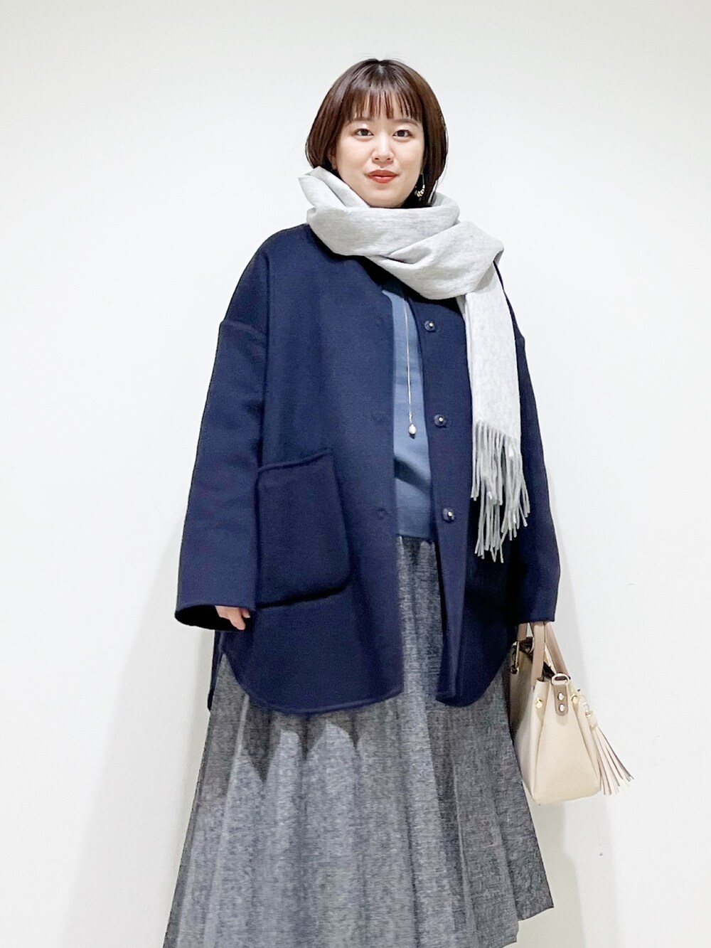 ブルー系のノーカラージャケット、グレー系のニット/セーター、ブルー系のスカートを着用したレディースの秋コーディネートの4枚目の写真