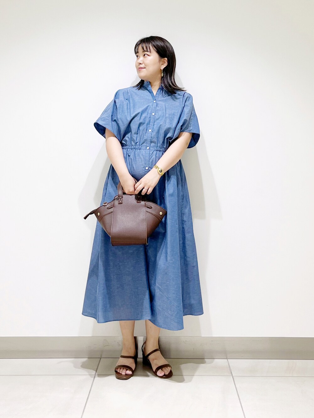 ブルー系のワンピース、ブラウン系のハンドバッグ、ブラウン系のサンダルを着用したレディースの夏コーディネートの3枚目の写真