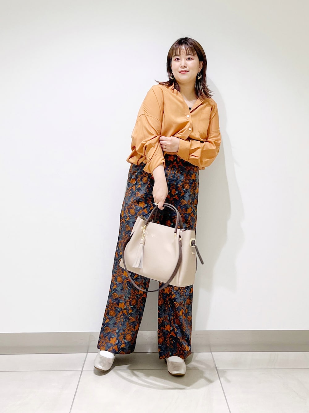 オレンジ系のシャツ/ブラウス、ベージュ系のトートバッグ、ゴールド系のその他シューズを着用したレディースの夏コーディネートの3枚目の写真