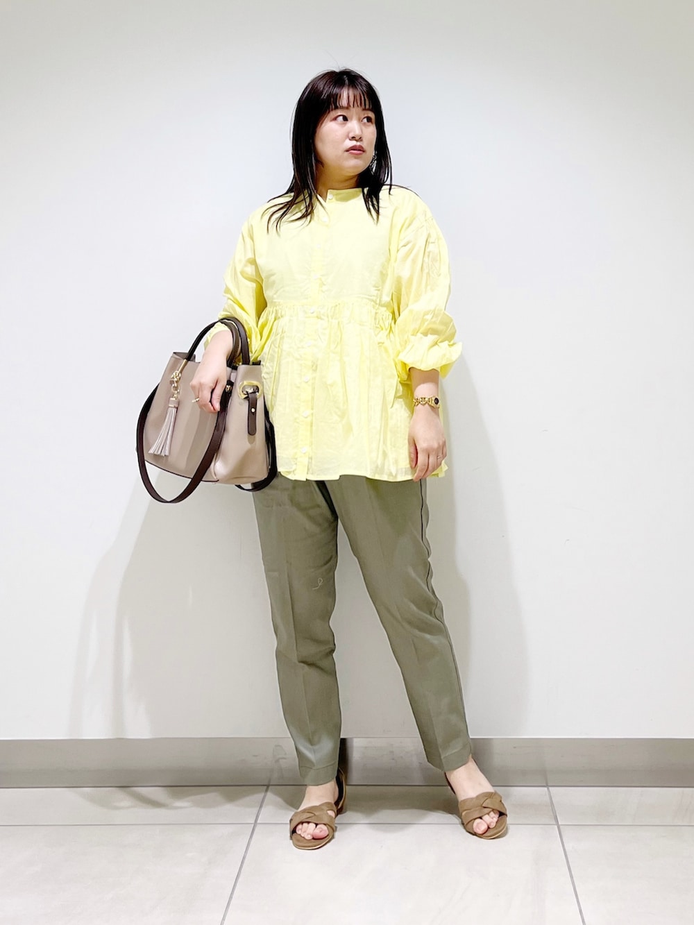 イエロー系のシャツ/ブラウス、グリーン系のその他パンツ、ベージュ系のトートバッグを着用したレディースの春コーディネートの3枚目の写真