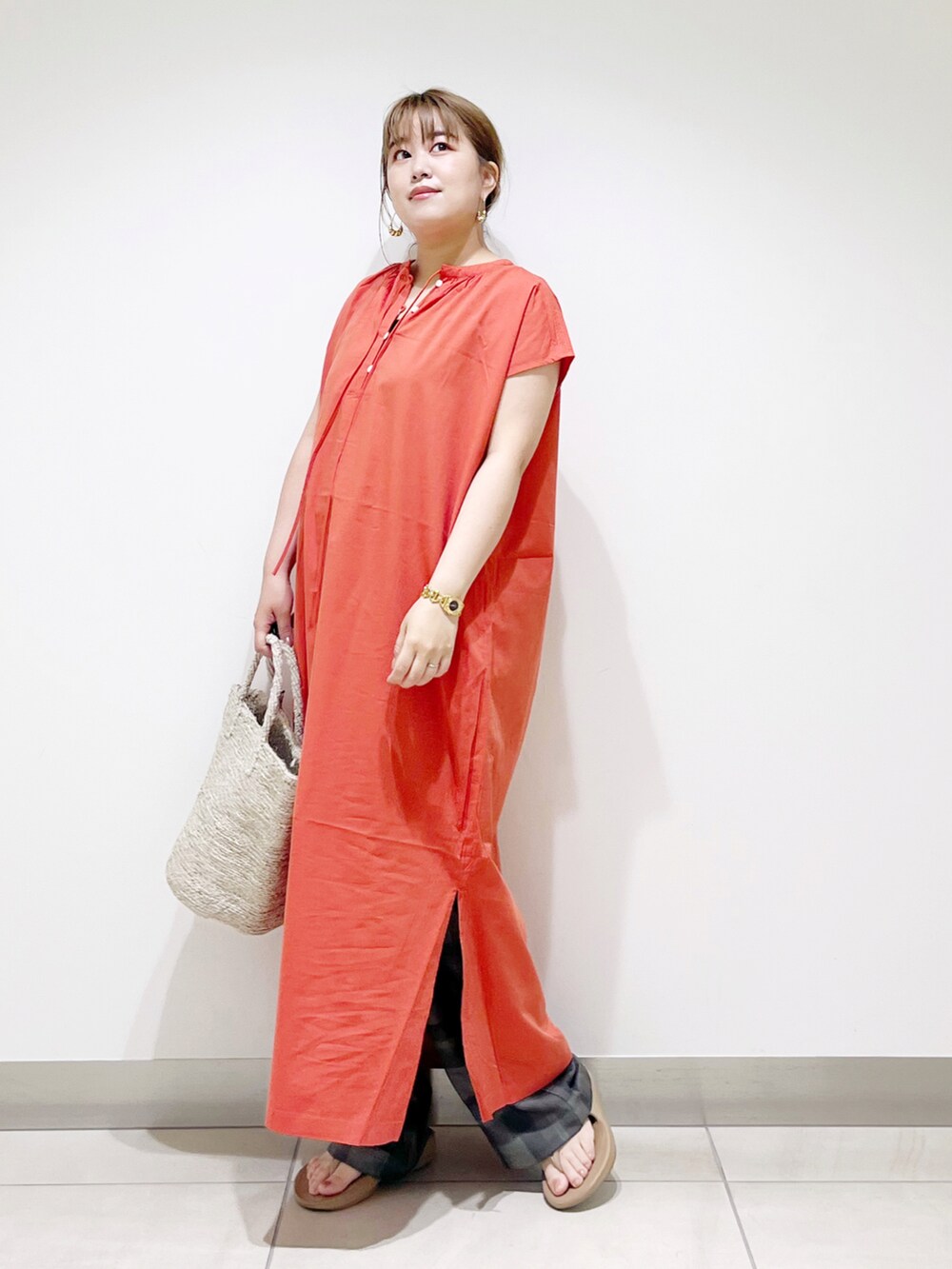 オレンジ系のワンピース、グレー系のトートバッグ、ベージュ系のサンダルを着用したレディースの春コーディネートの3枚目の写真