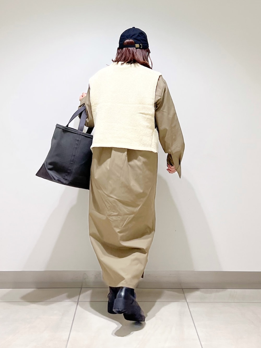 ホワイト系のベスト、グリーン系のワンピース、グレー系のトートバッグを着用したレディースの秋コーディネートの7枚目の写真