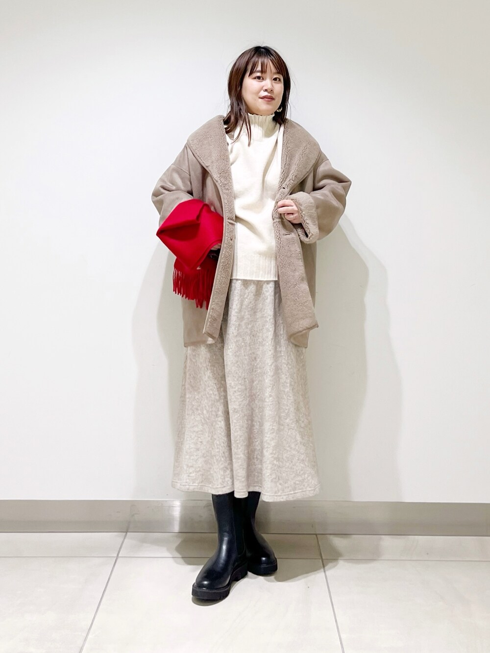 グレー系のムートンコート、ホワイト系のニット/セーター、ベージュ系のスカートを着用したレディースの冬コーディネートの8枚目の写真