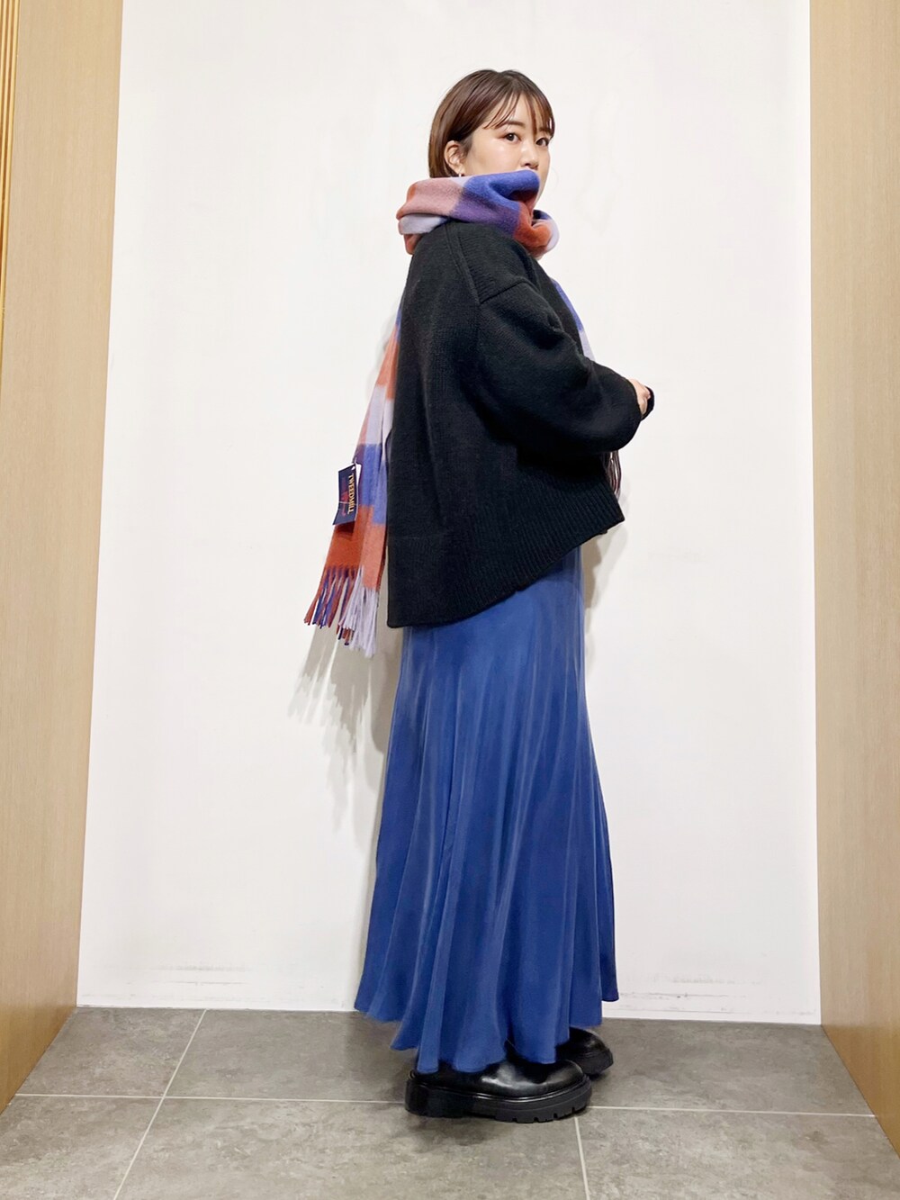 ブラック系のニット/セーター、ブルー系のスカート、ブラック系のブーツを着用したレディースの冬コーディネートの3枚目の写真