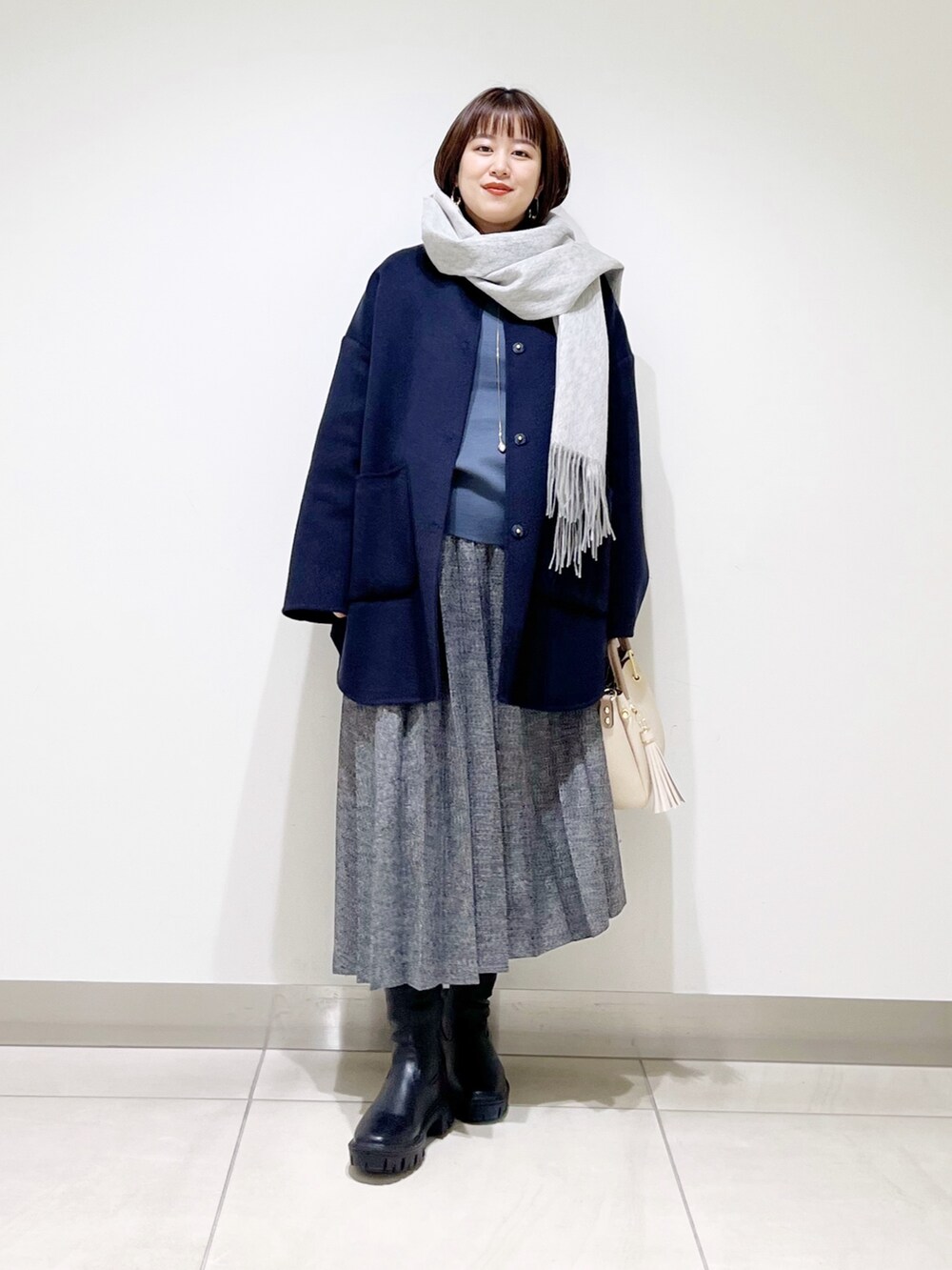 ブルー系のノーカラージャケット、グレー系のニット/セーター、ブルー系のスカートを着用したレディースの秋コーディネートの7枚目の写真