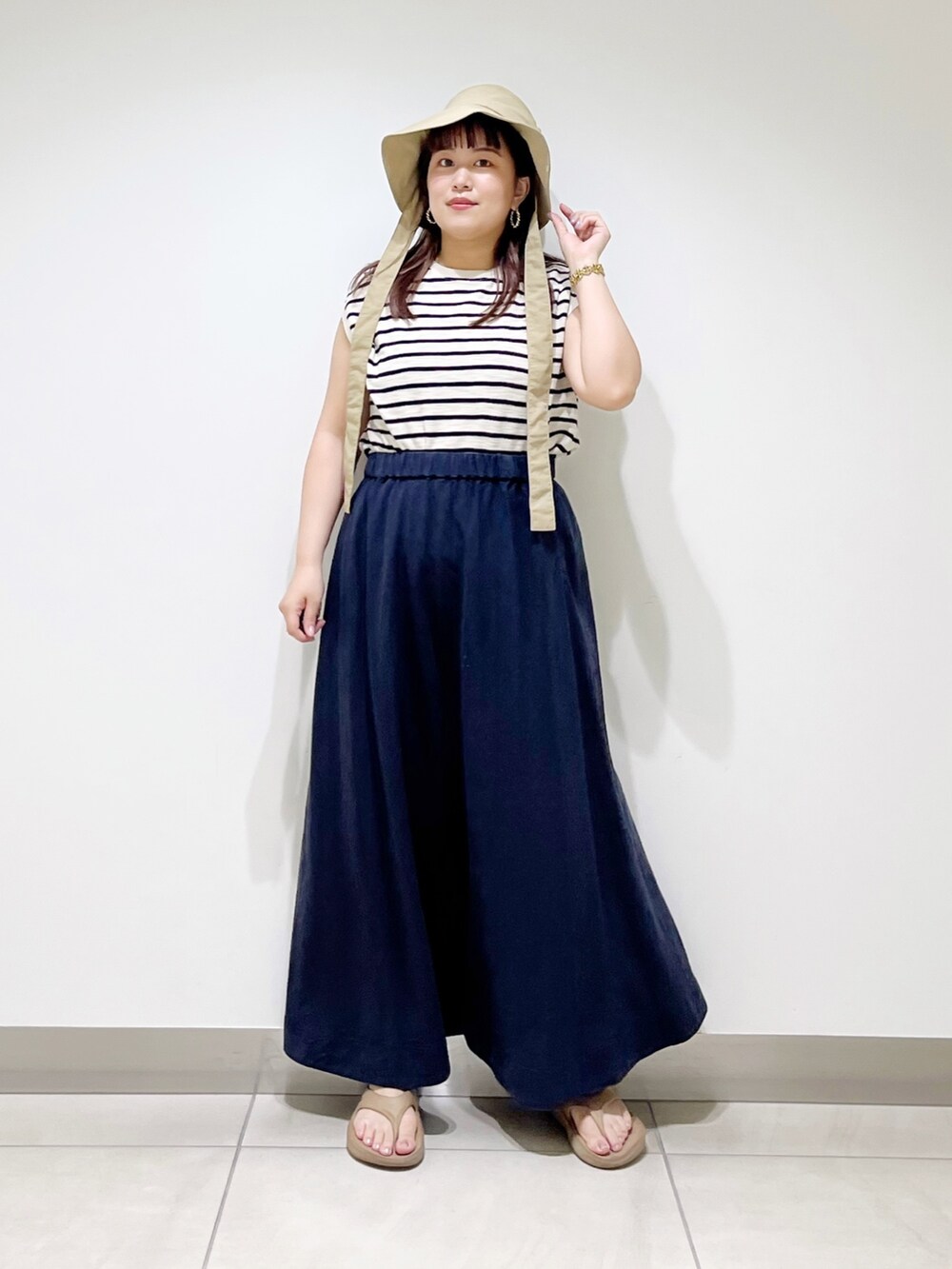 ベージュ系のTシャツ/カットソー、ブルー系のスカート、ベージュ系のサンダルを着用したレディースの夏コーディネートの9枚目の写真