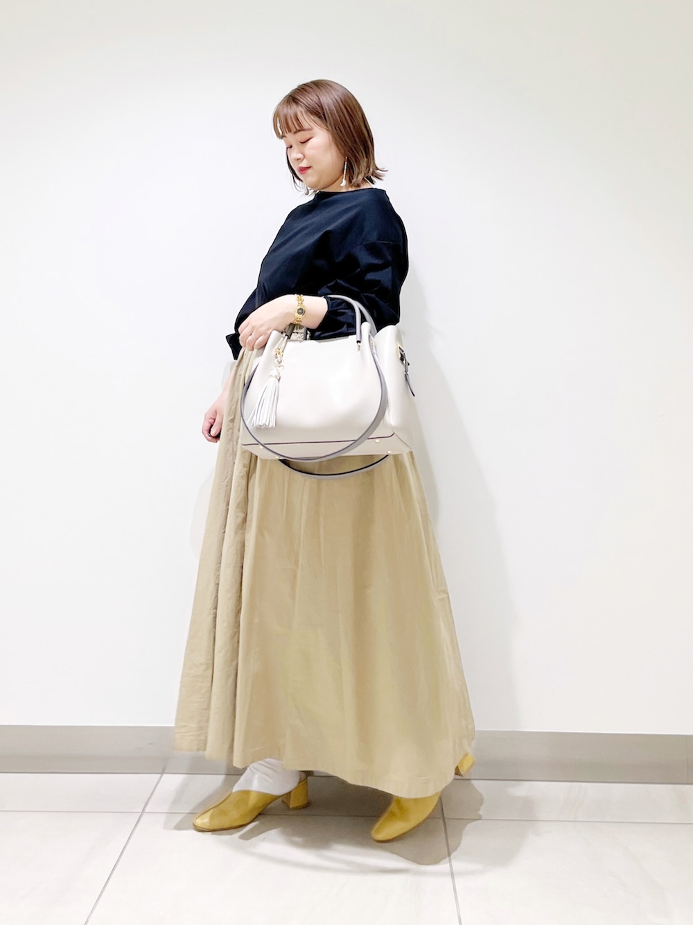 ブラック系のTシャツ/カットソー、ベージュ系のスカート、グレー系のトートバッグを着用したレディースの春コーディネートの3枚目の写真