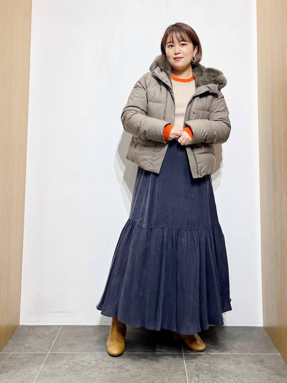 グリーン系のダウンジャケット/コート、ベージュ系のニット/セーター、ブルー系のスカートを着用したレディースの秋コーディネートの3枚目の写真