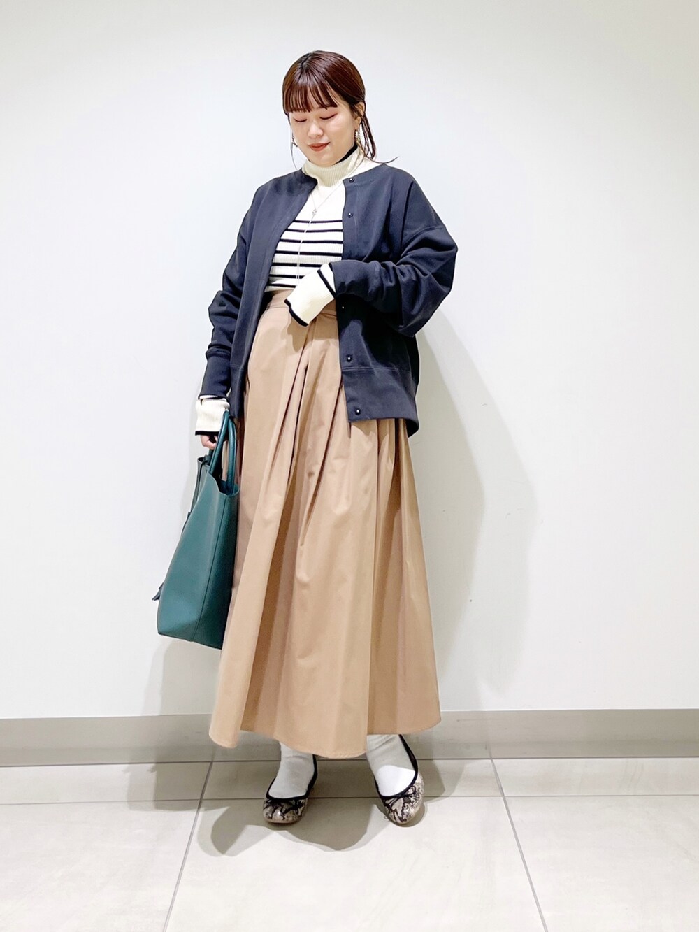 グリーン系のトートバッグ、ベージュ系のスカート、その他のバレエシューズを着用したレディースの秋コーディネートの9枚目の写真