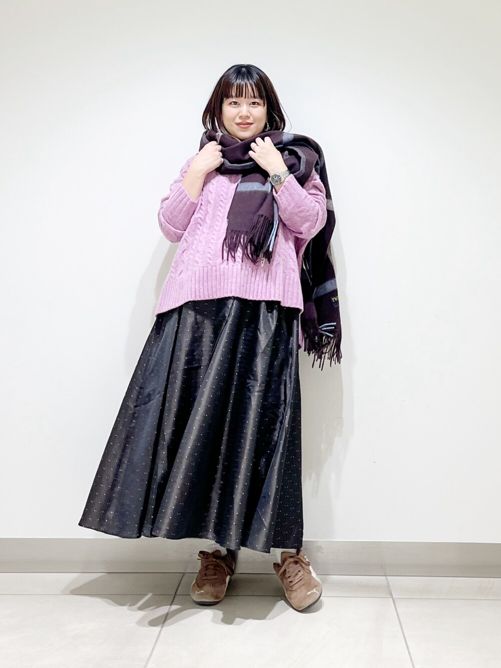 パープル系のニット/セーター、ブルー系のスカート、ブラック系のスニーカーを着用したレディースの秋コーディネートの10枚目の写真
