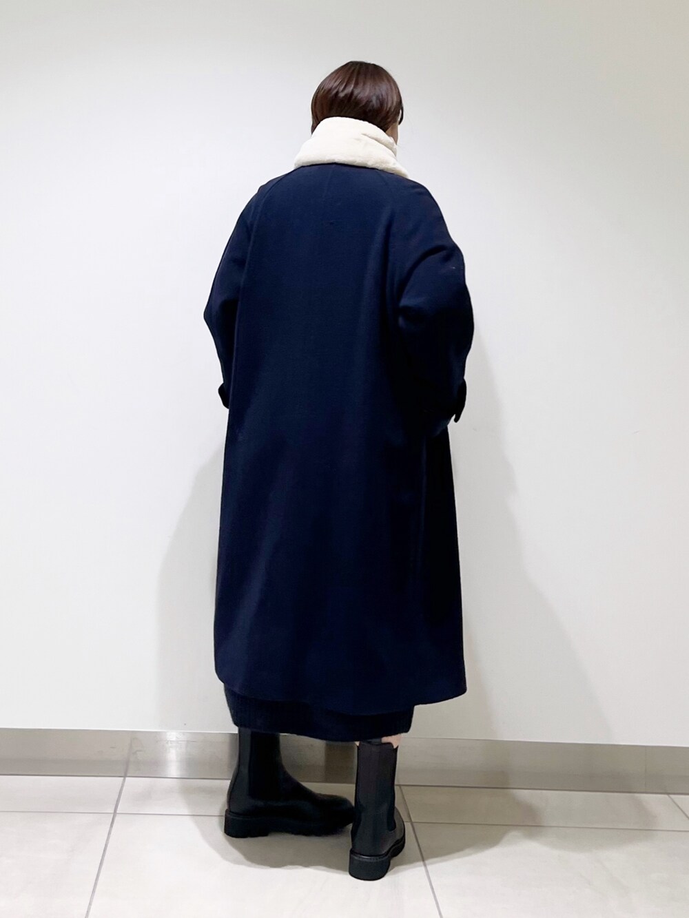 ブルー系のステンカラーコート、ブルー系のワンピース、ブラック系のブーツを着用したレディースの冬コーディネートの7枚目の写真