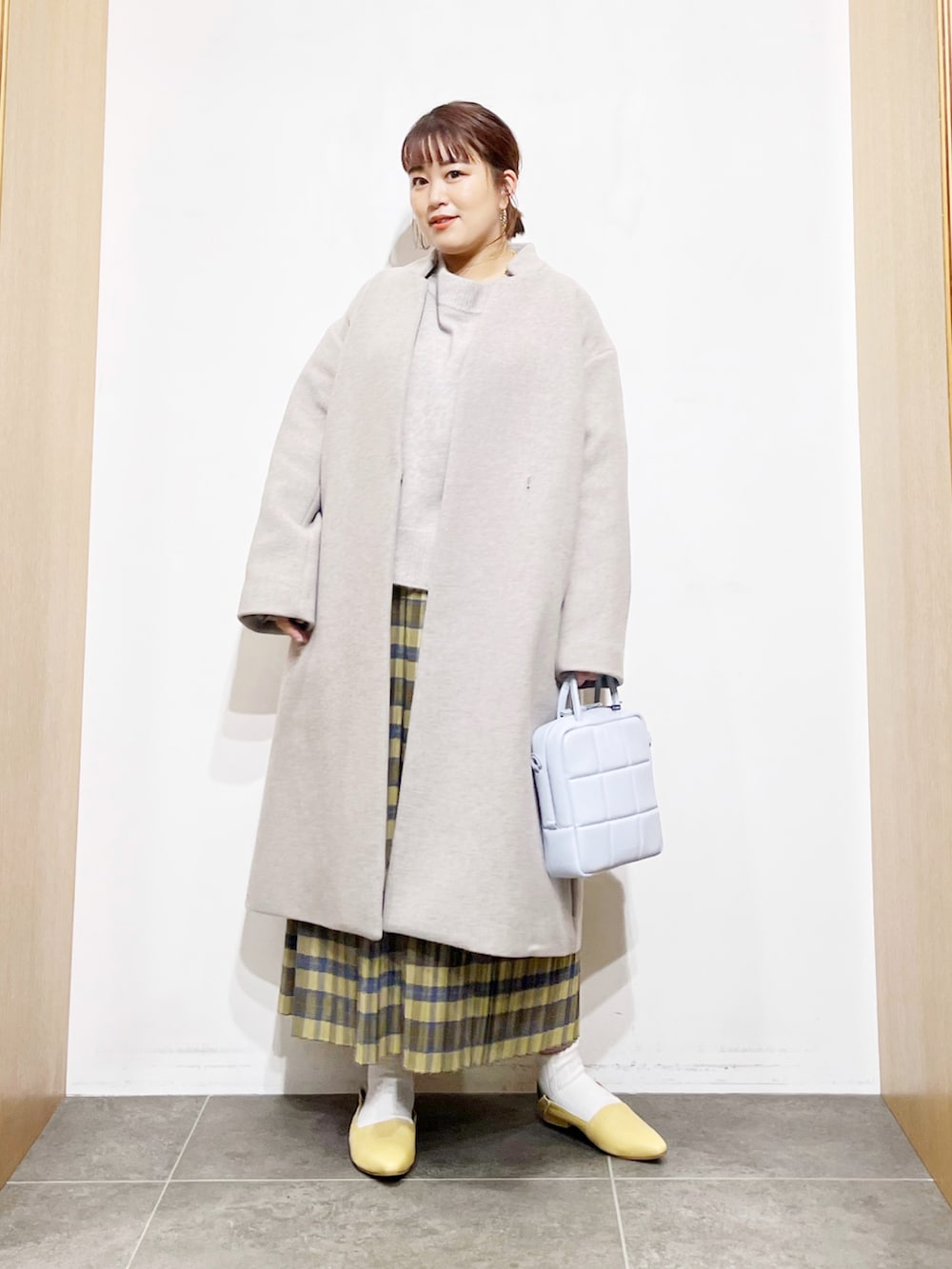 ベージュ系のニット/セーター、グレー系のその他アウター、イエロー系のスカートを着用したレディースの冬コーディネートの4枚目の写真