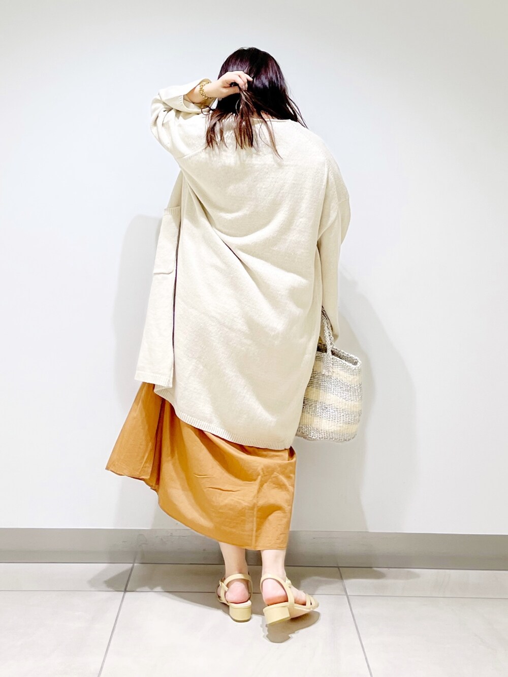 ブラウン系のワンピース、ホワイト系のカーディガン/ボレロ、ホワイト系のハンドバッグを着用したレディースの春コーディネートの4枚目の写真