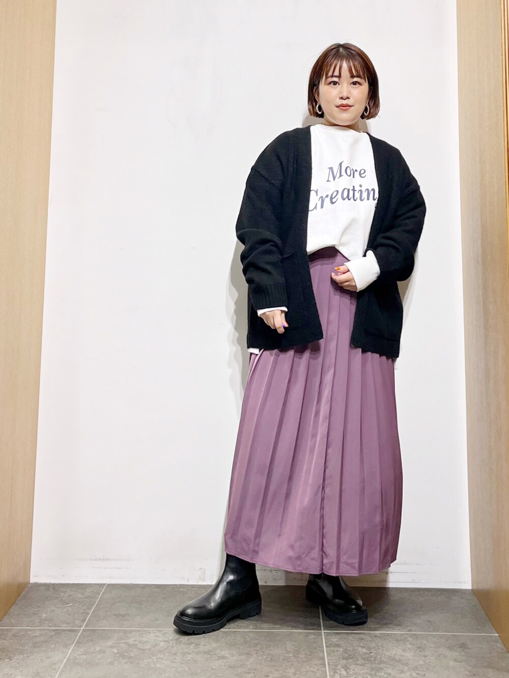 ホワイト系のTシャツ/カットソー、ブラック系のカーディガン/ボレロ、パープル系のスカートを着用したレディースの秋コーディネートの2枚目の写真