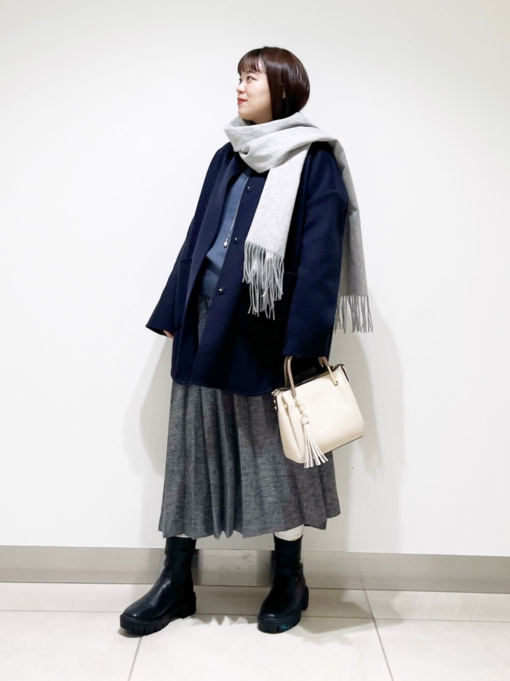 ブルー系のノーカラージャケット、グレー系のニット/セーター、ブルー系のスカートを着用したレディースの秋コーディネートの5枚目の写真