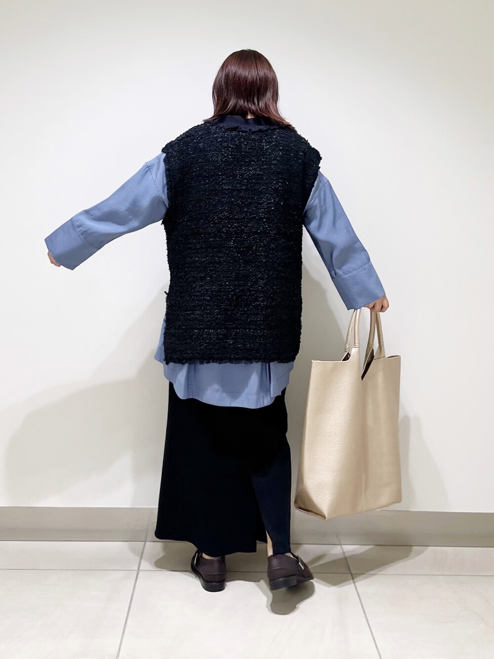 ブルー系のシャツ/ブラウス、ブラック系のスカート、ゴールド系のトートバッグを着用したレディースの秋コーディネートの4枚目の写真