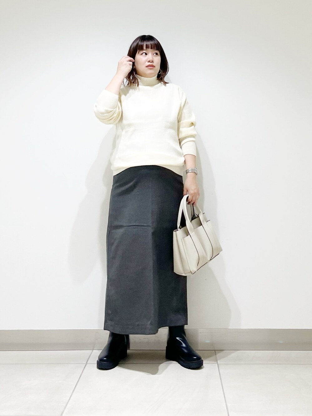ホワイト系のニット/セーター、ホワイト系のトートバッグ、グレー系のスカートを着用したレディースの秋コーディネートの5枚目の写真