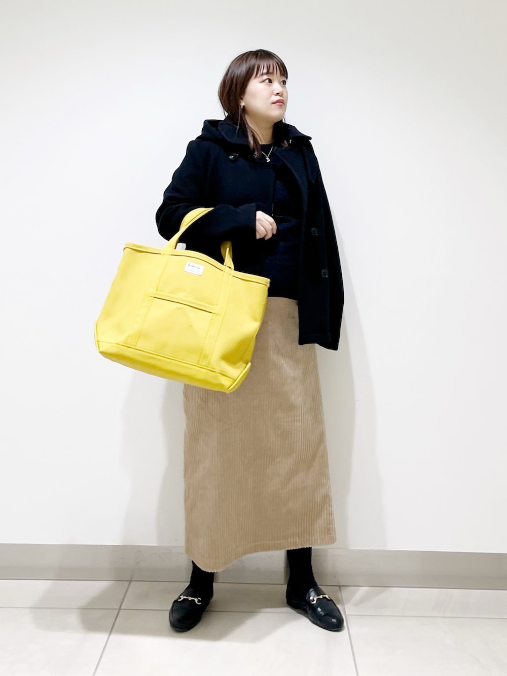 ブラック系のピーコート、ブルー系のニット/セーター、ブラック系のローファーを着用したレディースの冬コーディネートの9枚目の写真