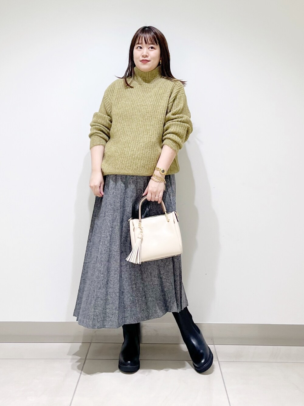 グリーン系のニット/セーター、ブルー系のスカート、ホワイト系のトートバッグを着用したレディースの冬コーディネートの10枚目の写真