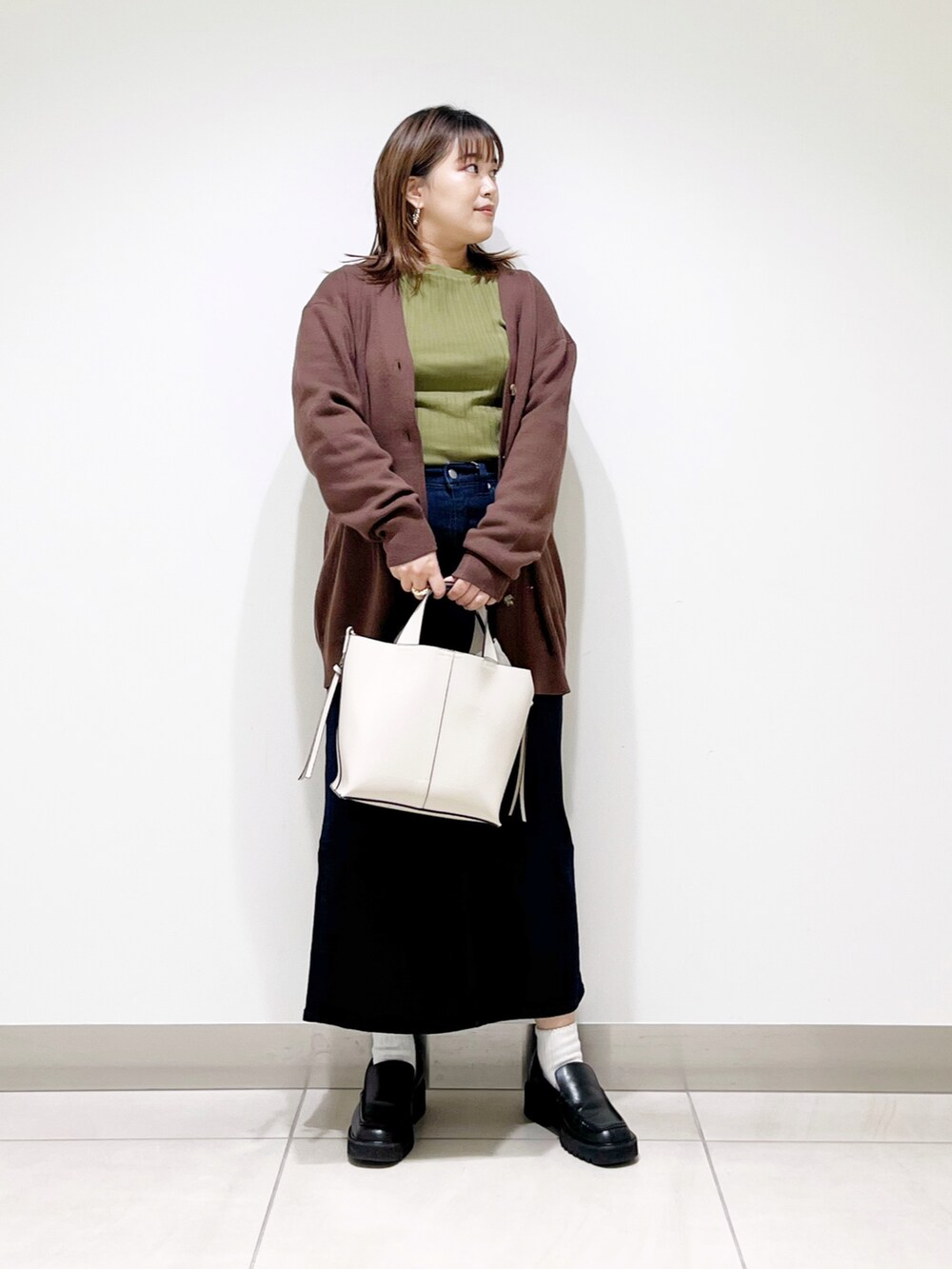ブラウン系のカーディガン/ボレロ、グリーン系のTシャツ/カットソー、ホワイト系のトートバッグを着用したレディースの秋コーディネートの2枚目の写真