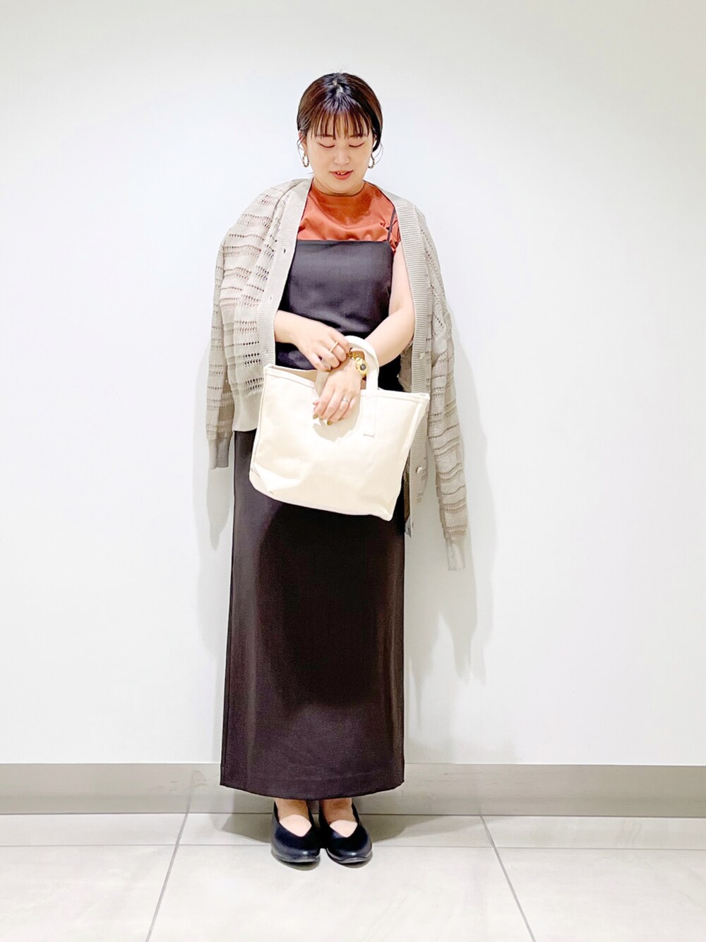 グレー系のワンピース、ホワイト系のトートバッグ、ブラック系のパンプスを着用したレディースの夏コーディネートの4枚目の写真