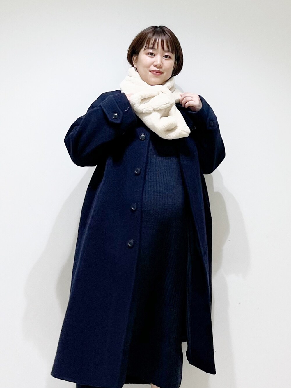 ブルー系のステンカラーコート、ブルー系のワンピース、ブラック系のブーツを着用したレディースの冬コーディネートの5枚目の写真