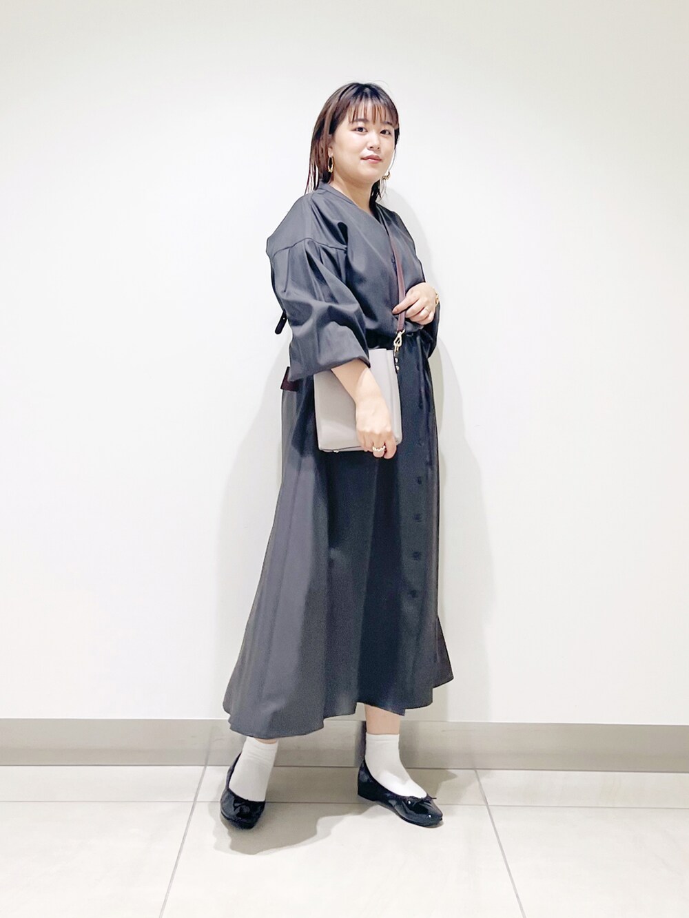 グレー系のワンピース、グレー系のショルダーバッグ、ブラック系のバレエシューズを着用したレディースの秋コーディネートの2枚目の写真