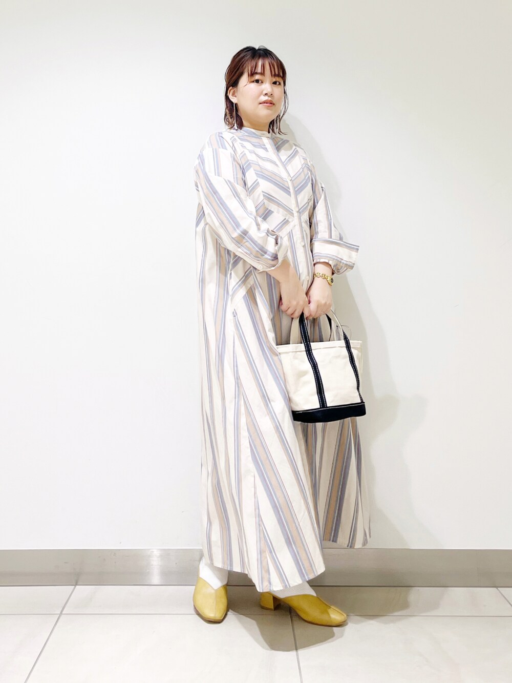 ベージュ系のワンピース、ブルー系のトートバッグ、イエロー系のその他シューズを着用したレディースの春コーディネートの2枚目の写真