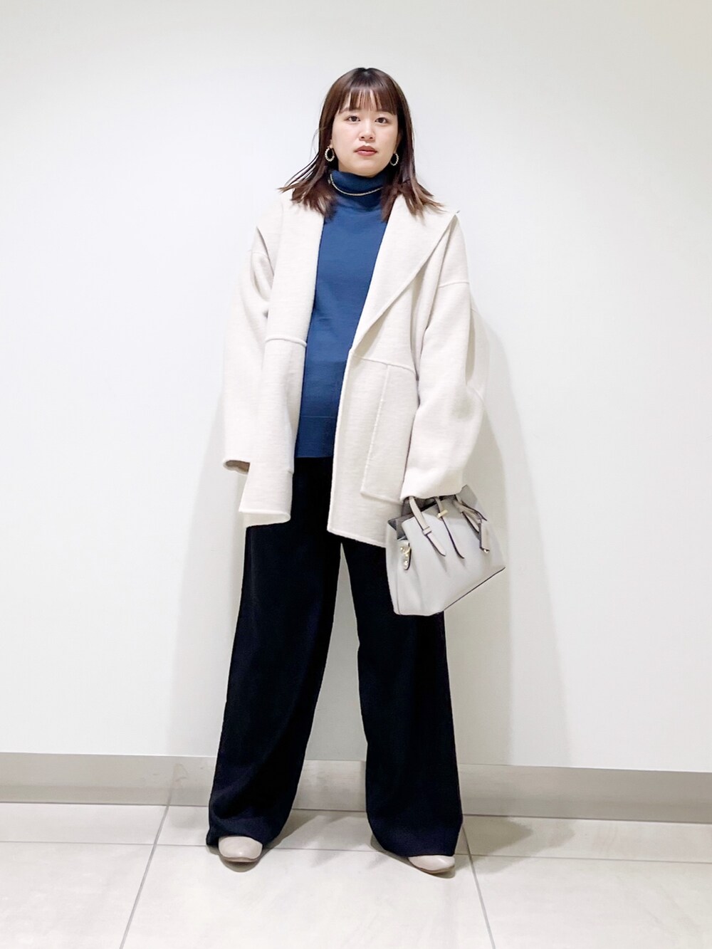 ベージュ系のその他アウター、ブルー系のニット/セーター、ブラック系のパンプスを着用したレディースの冬コーディネートの7枚目の写真