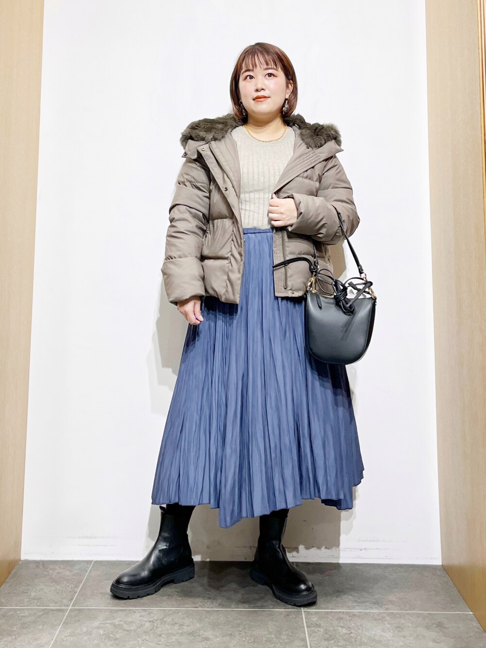 グリーン系のダウンジャケット/コート、ベージュ系のニット/セーター、ブラック系のショルダーバッグを着用したレディースの冬コーディネートの5枚目の写真